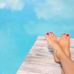 Bare woman feet by the swimming pool